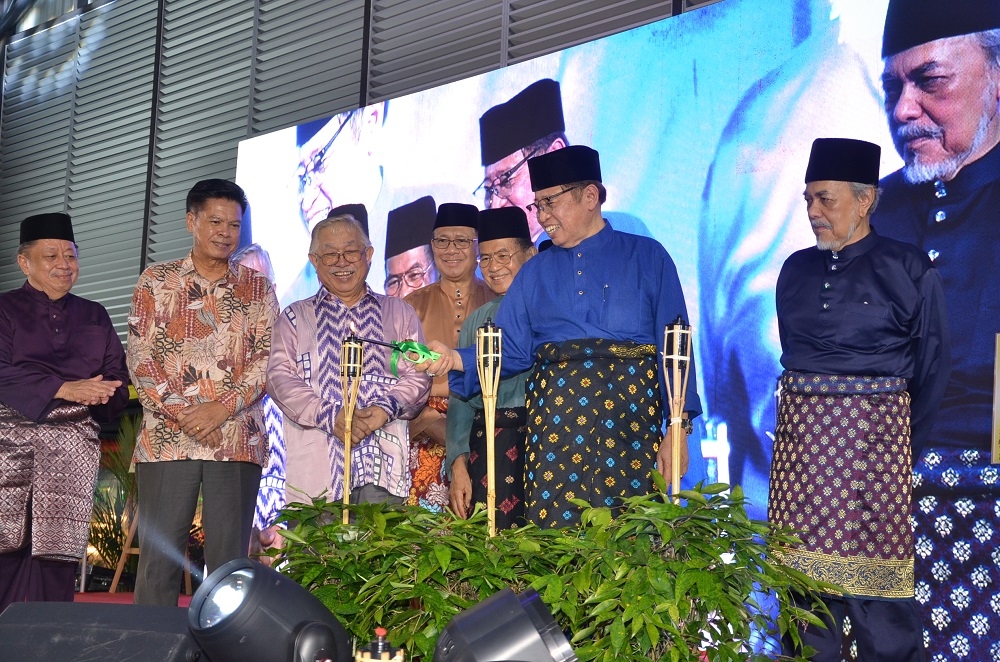 Sarawak Premier Datuk Patinggi Tan Sri Abang Johari Tun Openg lights traditional oil lamps during the Aidilfitri gathering. From left are Haidar, Majang, Sikie, Julaihi, Talib, and Asfia. ― Borneo Post pic