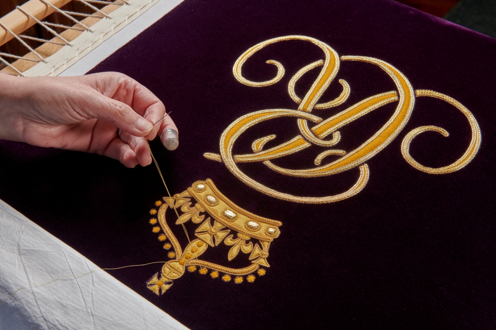 An undated handout photo issued by Buckingham Palace shows a member of the Royal School of Needlework hand embroidering the Queen Consort's cypher onto her Robe of Estate, which she will wear at the coronation on May 6. — Reuters pic