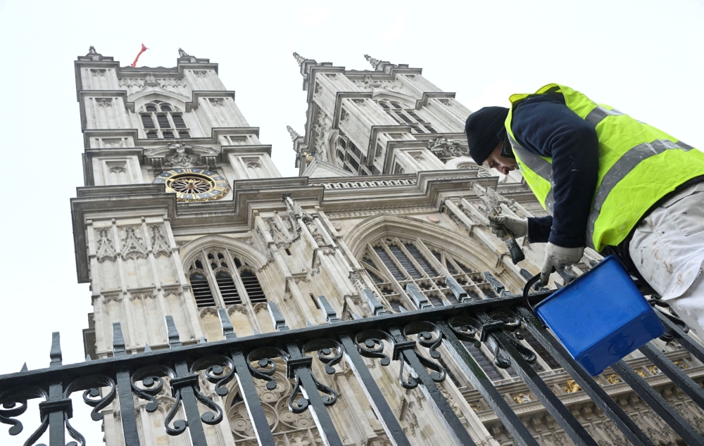 A worker paints railings in preparation of the Coronation of King Charles III, outside of Westminster Abbey in London April 19, 2023. — Reuters pic