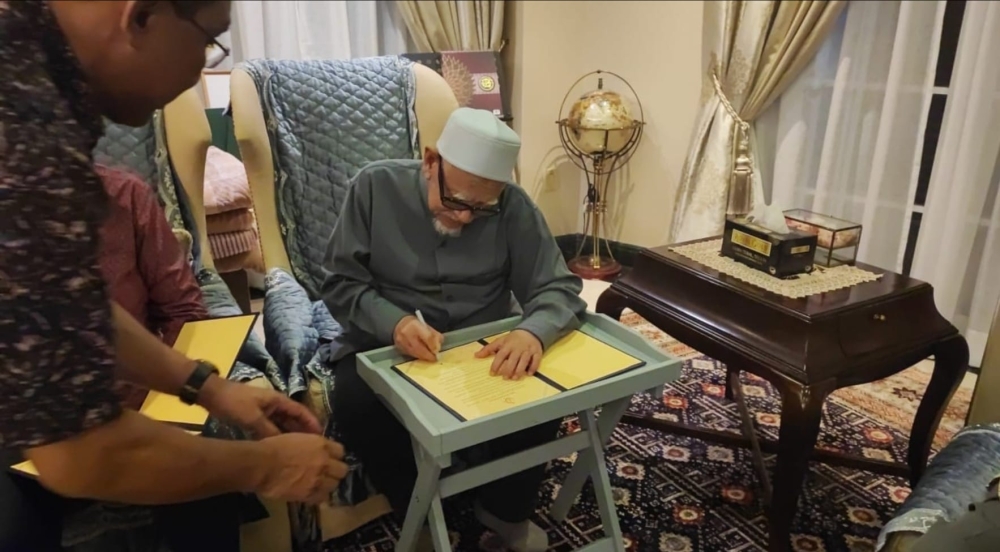 Dr Mahathir’s aide, Abu Bakar Yahya, posted a picture on Facebook yesterday showing Hadi signing the document to support the Malay cause. — Picture courtesy of Facebook