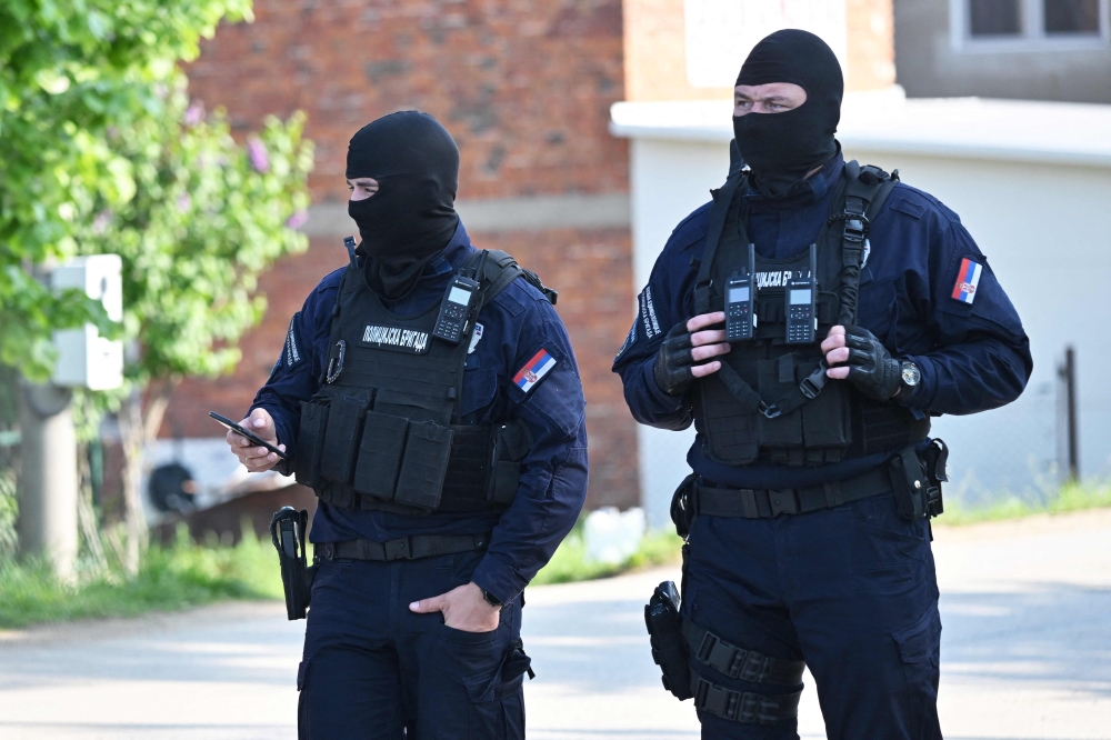 Masked policemen secure an area in the village of Dubona near the town of Mladenovac, about 60 kilometres south of Serbia’s capital Belgrade, on May 5, 2023, in the aftermath of a drive-by shooting. — AFP pic