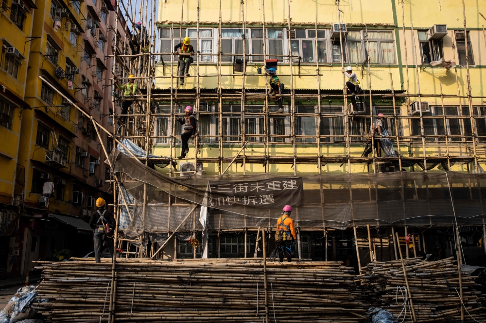 Scaffolders taking down bamboo scaffolding from a residential building at the Kowloon district in Hong Kong March 2, 2023. — AFP pic