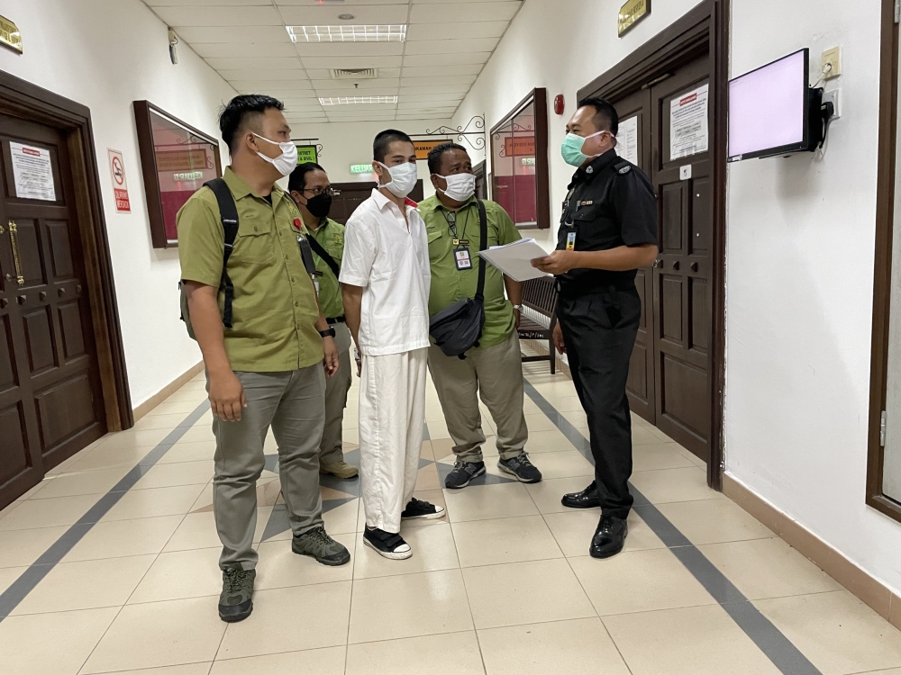 Kuan is escorted by SFC officers at the court. — Borneo Post pic