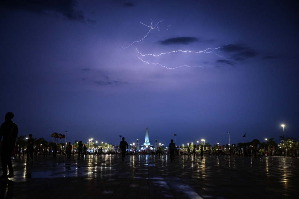 Lightning lights up the sky as people arrive to attend the closing ceremony of the 32nd South-east Asian Games (SEA Games) at the Morodok Techo National Stadium in Phnom Penh May 17, 2023. — AFP pic