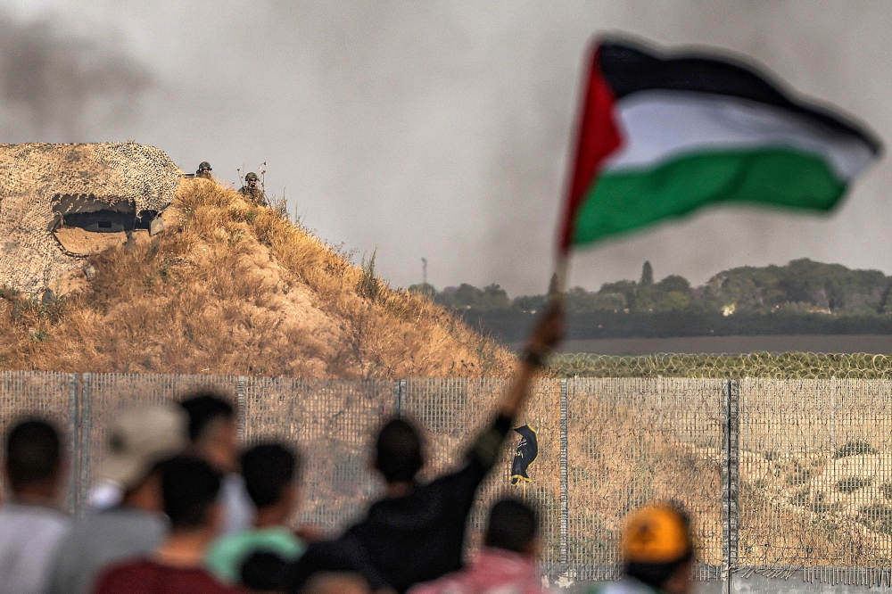 In Gaza, thousands gathered for a rival flag day on the Israeli border, many of them holding Palestinian flags. — AFP pic