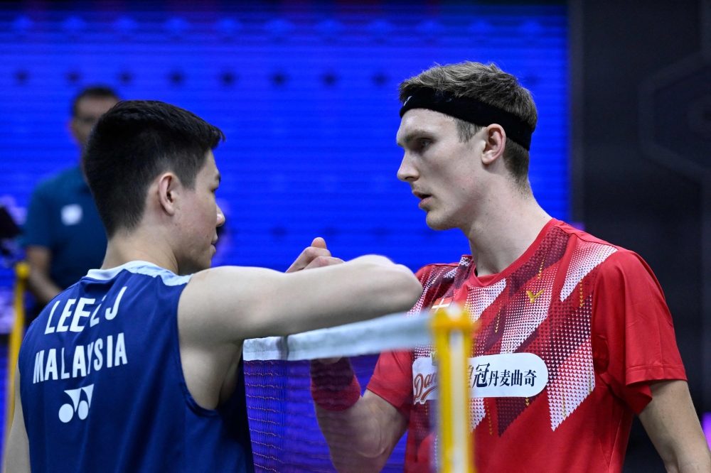 Malaysia's Lee Zii Jia (left) shakes hands with Denmark's Viktor Axelsen after he retired during the men's singles quarter-final match against at the 2023 Sudirman Cup world badminton championships in Suzhou in China's eastern Jiangsu province May 19, 2023. — AFP pic