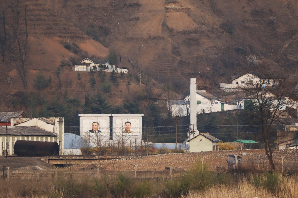 Buildings in North Korea's Sinuiju with giant portraits of late North Korean leaders Kim Il Sung and Kim Jong Il are seen from China's Dandong, Liaoning province, China April 20, 2021. — Reuters pic