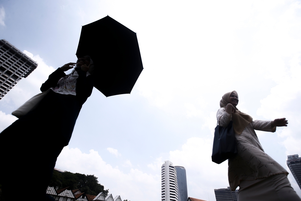 Pedestrians use umbrellas to shield the sunlight during hot weather in Kuala Lumpur, May 17, 2023. — Picture by Hari Anggara