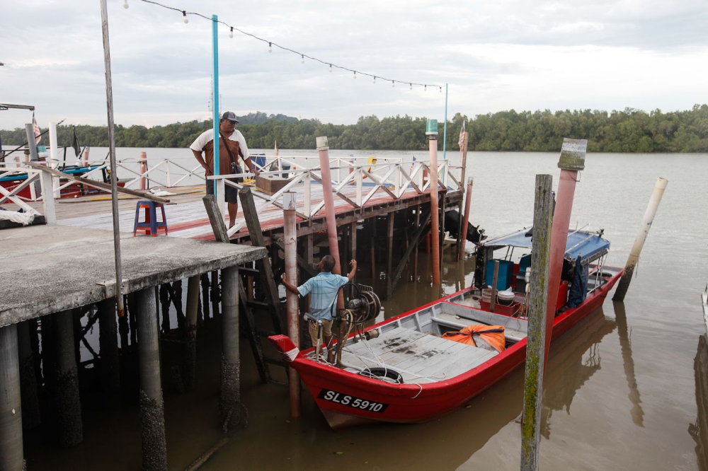 Lim Kee Hwa (left) and crewmate Teo Kun Chui (right) prepare their fishing equipment before leaving. — Picture by Sayuti Zainudin