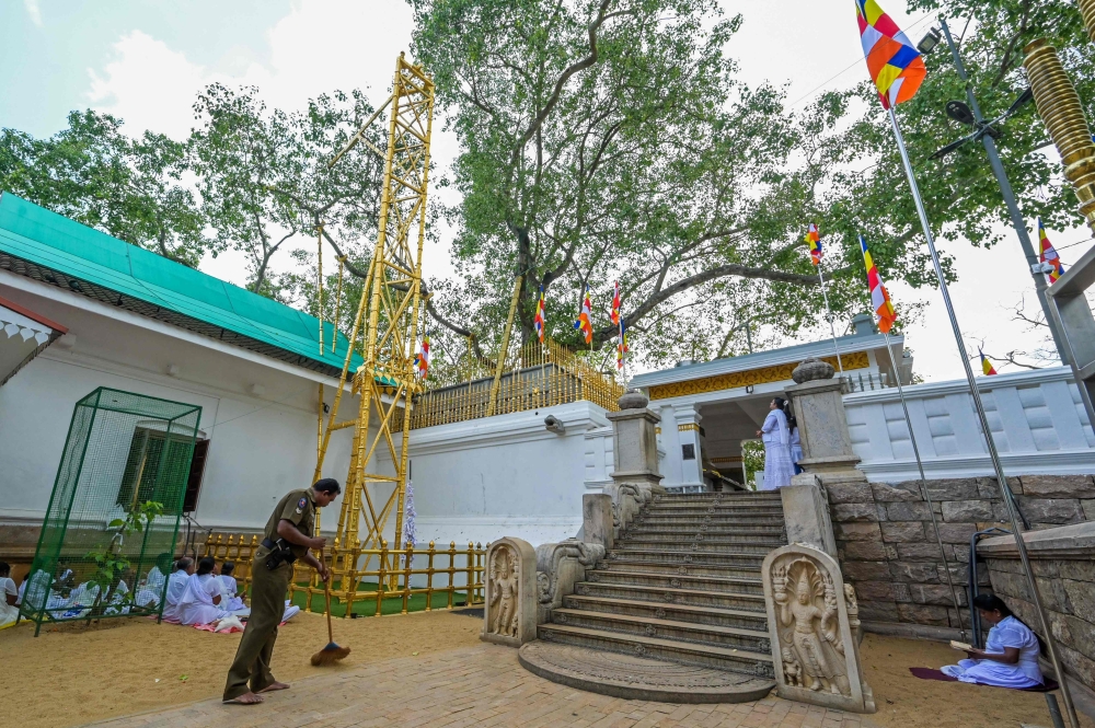 A policeman sweeping in front of the ancient bodhi tree at Sri Maha Bodhi temple in Anuradhapura. — AFP pic