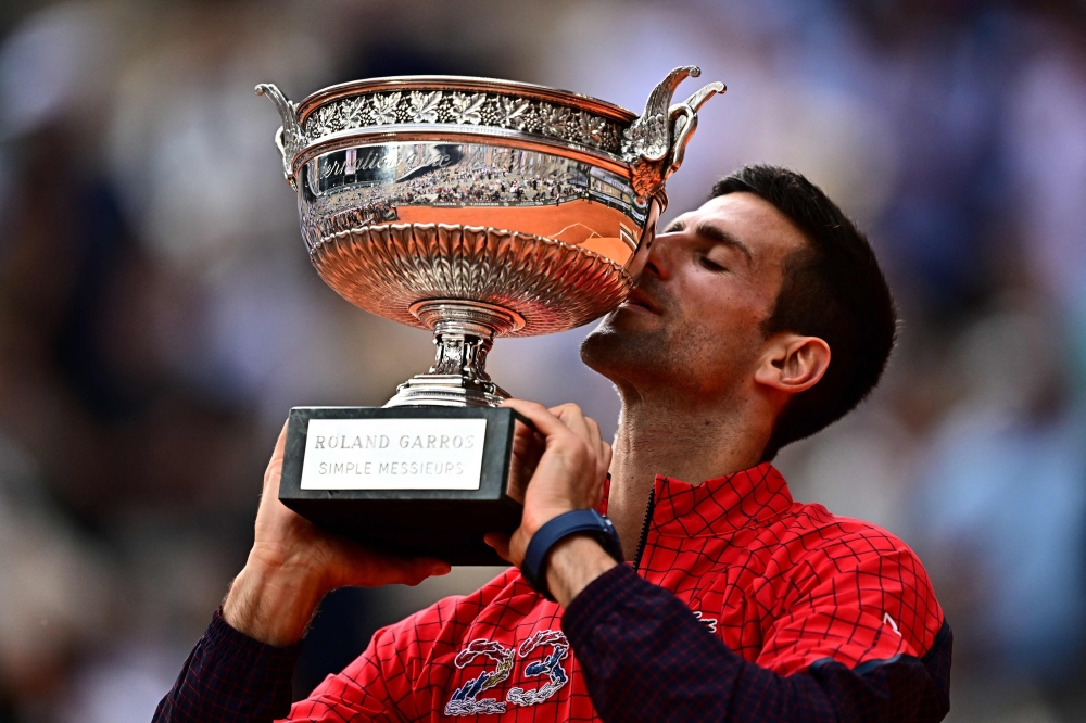 Serbia's Novak Djokovic kisses his trophy as he celebrates his victory over Norway's Casper Ruud during their men's singles final match on day fifteen of the Roland-Garros Open tennis tournament at the Court Philippe-Chatrier in Paris June 11, 2023. — AFP pic