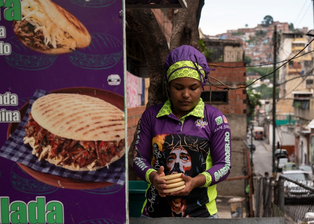 A woman cooks on a griddle the traditional Venezuelan food known as arepas (stuffed cornmeal tortillas) at a food truck parked on a street of the popular neighbourhood of Santa Rosalia, located in the historic centre of Caracas on May 31, 2023. — AFP pic 