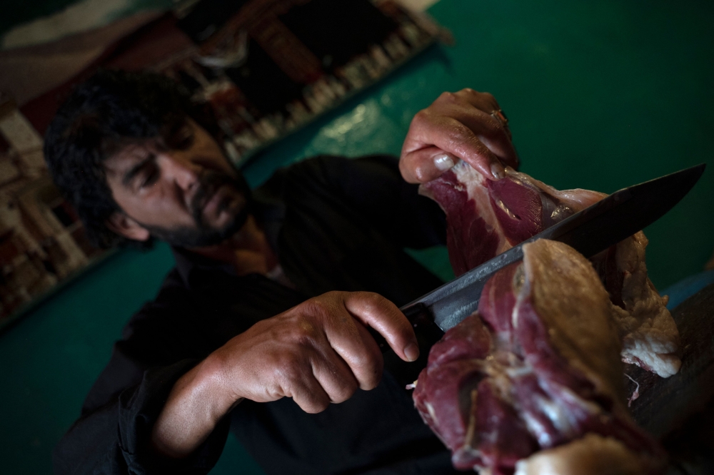 Foto yang diambil pada 14 Jun 2023 ini menunjukkan chef Afghanistan dan pemilik restoran Waheed memotong daging kambing untuk menyediakan rebusan hidangan kambing Chainaki tradisional.  — Gambar AFP