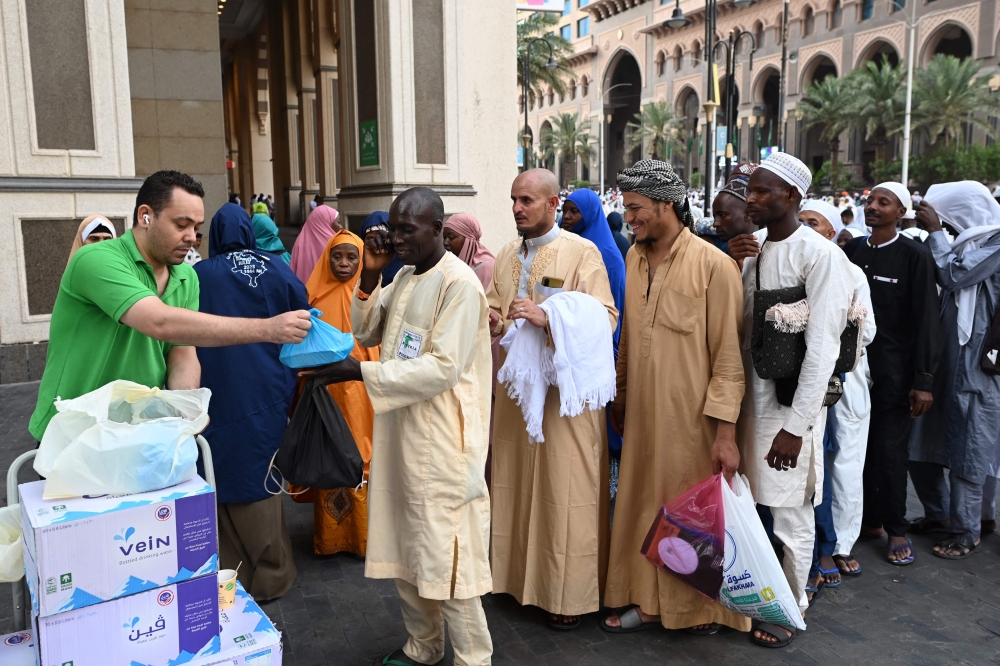 A volunteer hands out food packages offered by the residents of Mecca to pilgrims. — AFP pic