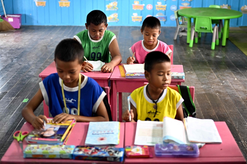 This photograph taken on June 14, 2023 shows the four students Jiranan Chorsakul (2nd right), Cholthee Chorsakul (right), Napat Ploykhow (2nd left), and Peeraphab Butrthong (left) studying inside a classroom in their school in Ban Khun Samut Chin, a coastal village less than 10km from the edge of Bangkok. — AFP pic 