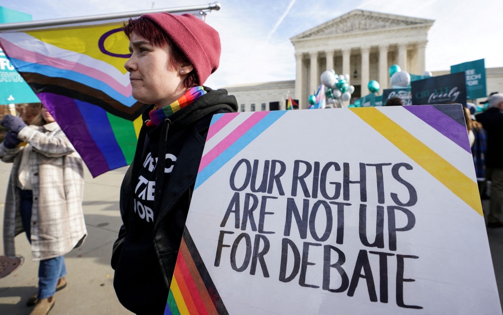 File photo of a protester carrying a sign as activists demonstrate outside the US Supreme Court, where justices were set to hear arguments in a major case pitting LGBT rights against a claim that the constitutional right to free speech exempts artists from anti-discrimination laws in a dispute involving an evangelical Christian web designer who refuses to provide her services for same-sex marriages, in Washington, US, December 5, 2022.— Reuters pic