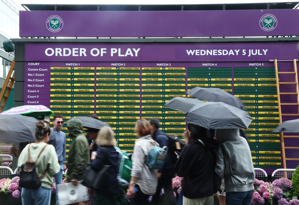 Spectators take cover as play on the outer courts is suspended due to rain, London, Britain. July 5, 2023. — Reuters pic 