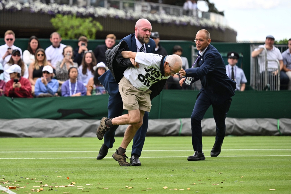 A Just Stop Oil demonstrator is escorted out of court 18 after disrupting the women’s singles tennis match between Australia’s Daria Saville and Britain’s Katie Boulter on the third day of the 2023 Wimbledon Championships at The All England Tennis Club in Wimbledon, south-west London, on July 5, 2023. — AFP pic 