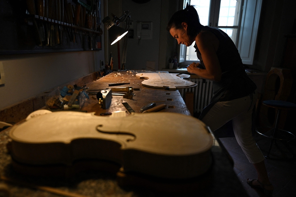 Pembuat biola Perancis Benedicte Friedmann bekerja pada badan cello di bengkel Cremonanya, pada 4 Julai 2023. — Gambar AFP