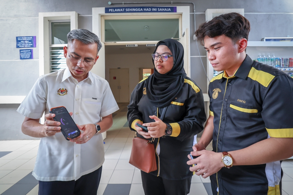 (From left) Communications and Digital Minister Fahmi Fadzil shows the internet speed test result on his mobile phone to UiTM Selangor Branch Tualang College Representative Committee president Muhammad Syafiq Akmal Mahadi and Dahlia College Representative Committee president Nur Amani Izzati Kamarul Azhar during the former’s visit to the Dengkil campus of UiTM Selangor branch July 9, 2023. — Bernama pic