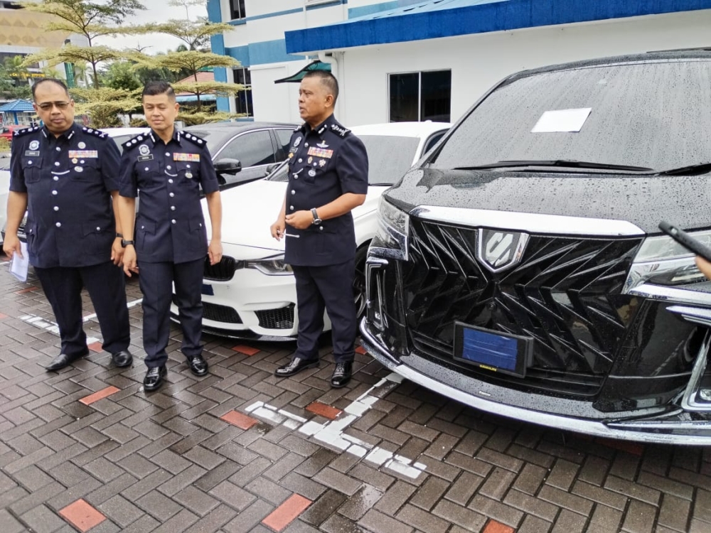 Johor police chief Datuk Kamarul Zaman Mamat (right) with the seized luxury vehicles belonging to the illegal money lending syndicate at the Johor police contingent headquarters in Johor Baru July 14, 2023. — Picture by Ben Tan