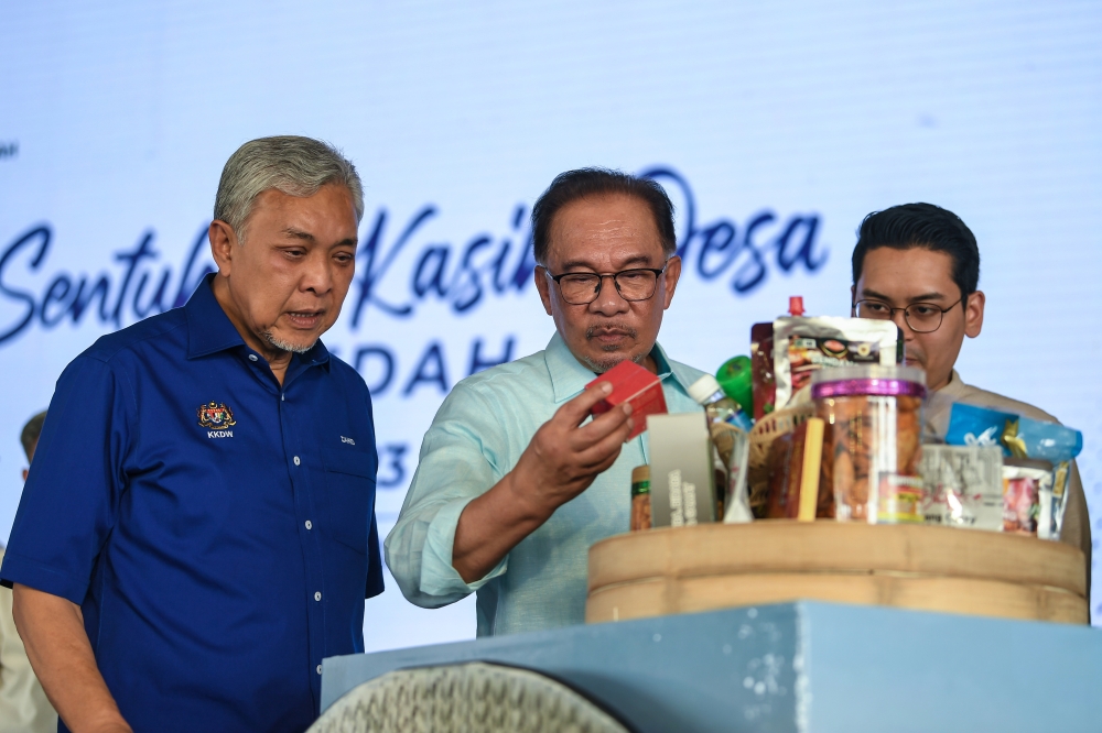 Prime Minister Datuk Seri Anwar Ibrahim (centre) and Deputy Prime Minister Datuk Seri Ahmad Zahid Hamid (left) look at products on offer during the launch of the mini carnival for rural entrepreneurs at Sungai Petani July 15, 2023. — Bernama pic 