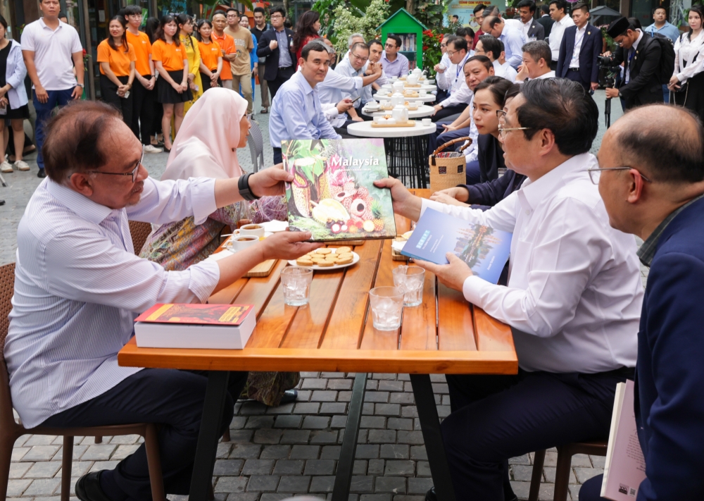 Prime Minister Datuk Seri Anwar Ibrahim presents a book to his Vietnamese counterpart Pham Minh Chinh during their visit to Hanoi Book Street July 21, 2023. — Bernama pic