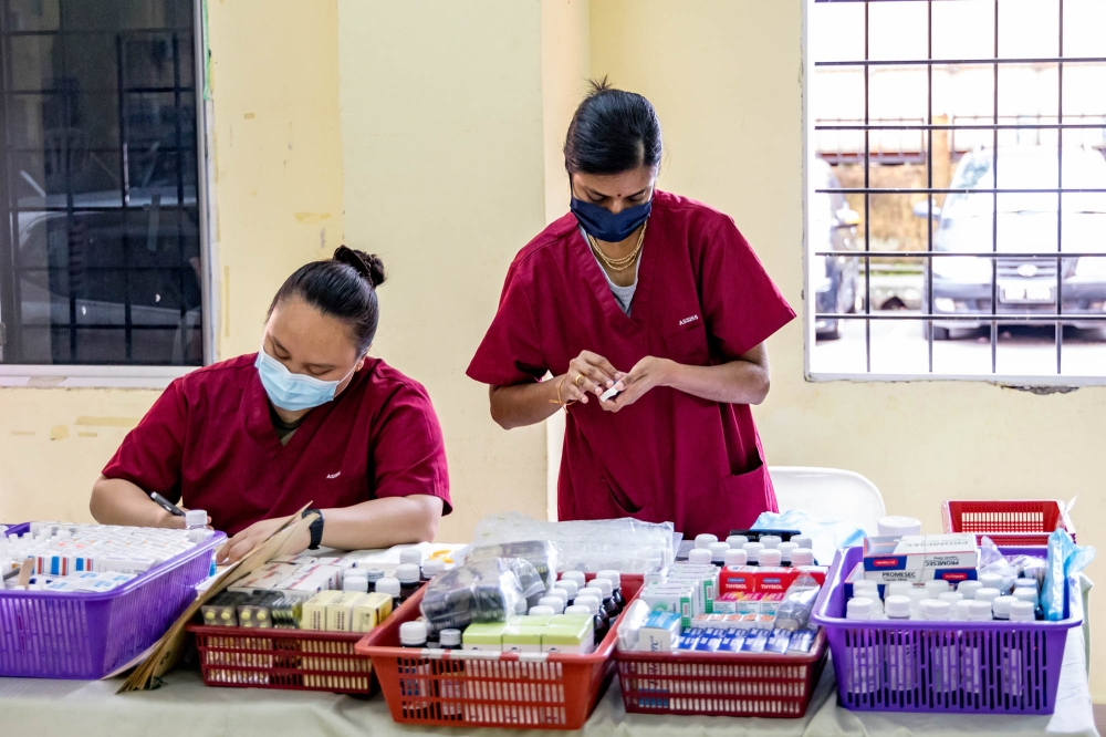 Edeena Marcellena Engel (left) with colleague Valarmathi Magendran checking medication on Assunta Mobile Clinic duty at PPR Kampung Baru Air Panas in Kuala Lumpur July 12, 2023. — Picture by Firdaus Latif