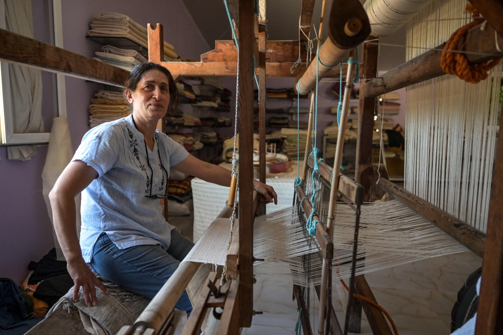 Emel Duman, owner of Appollon Defne silk, poses as she weaves silk fabric in Antakya on July 10, 2023. — AFP pic