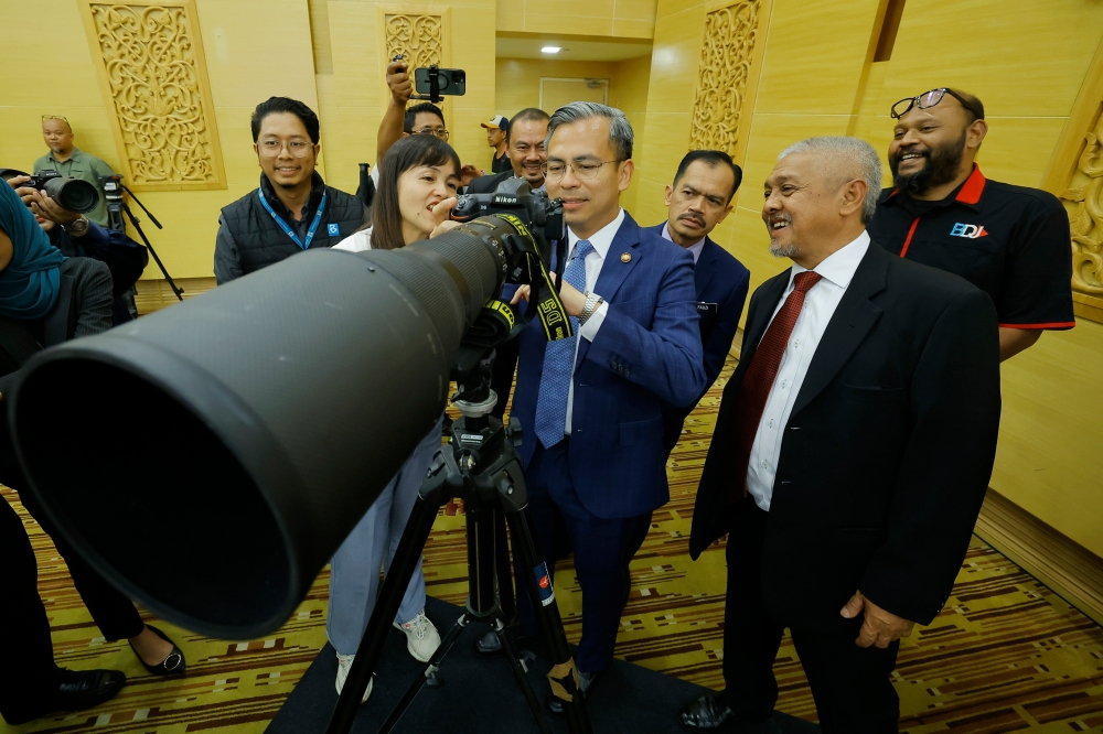 Communications and Digital Minister Fahmi Fadzil looks at equipment used by photographers during the monthly gathering of the Ministry of Communications and Digital in Putrajaya, July 31, 2023.  — Bernama pic  