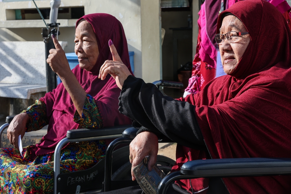 Fatimah Salleh, 80 and Che Basah Abdullah, 70 (right) show their fingers that have been dyed with permanent ink after voting for the State Assembly (DUN), in the state election in Sekolah Jenis Kebangsaan (C) Pei Yu, August 12, 2023. — Bernama pic