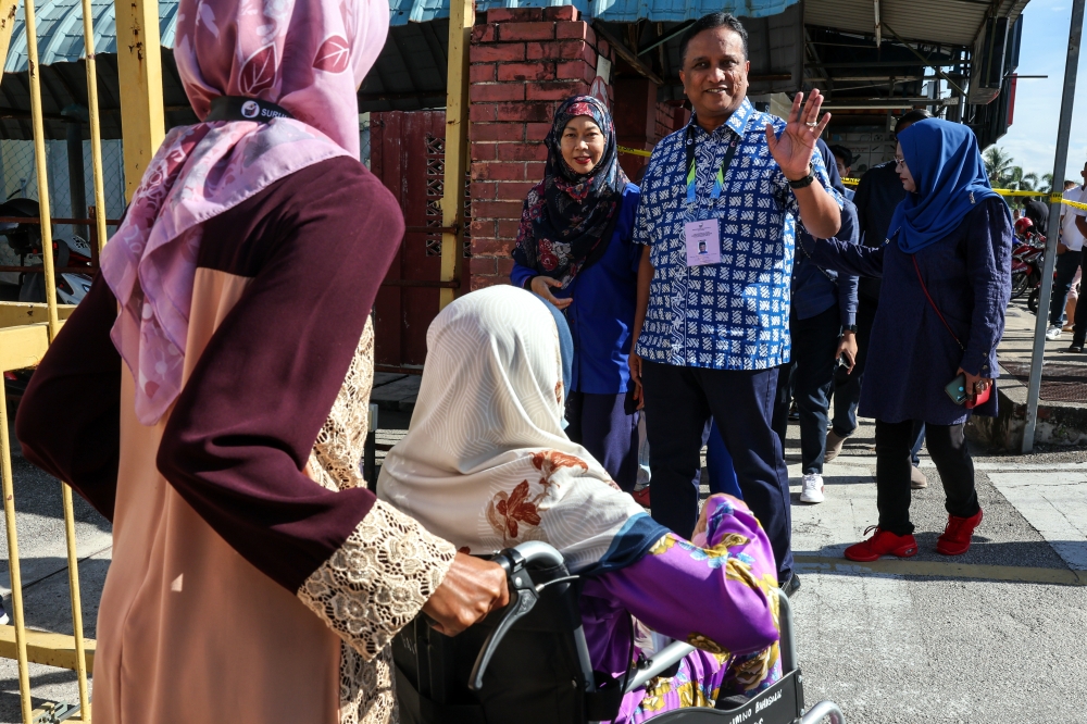 BN candidate for the Bertam state seat, Datuk Seri Reezal Merican Naina Merican accompanied by his wife Datin Seri Ismalina Ismail greet voters at Sekolah Jenis Kebangsaan (C) Pei Yu. — Bernama pic