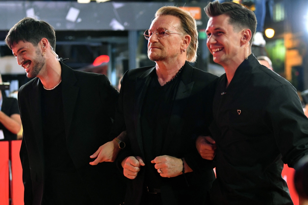 U2 singer Bono (centre) arrives, escorted by orgnaisers at the red carpet area, in front of Bosnian National Theater before premiere of the motion picture ‘Kiss The Future’, during grand opening ceremony of the 29th edition of Sarajevo Film Festival in Sarajevo, on August 11, 2023. — AFP pic