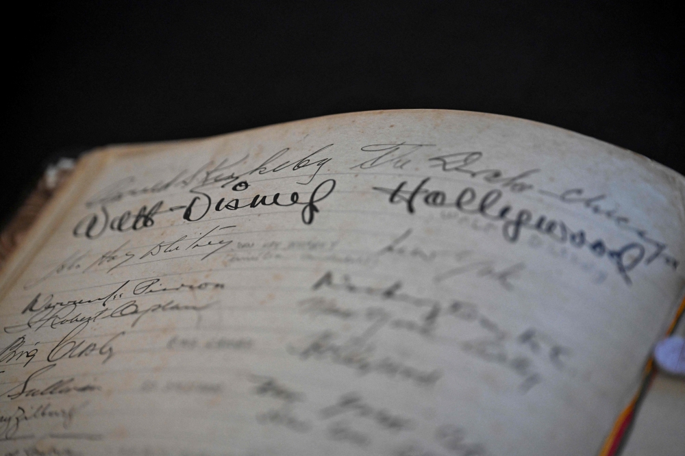 A hotel worker shows the signature of the late founder of the Disney company, Walt Disney (1901–1966), on the Golden Book of the Belmond Copacabana Palace Hotel. — AFP pic