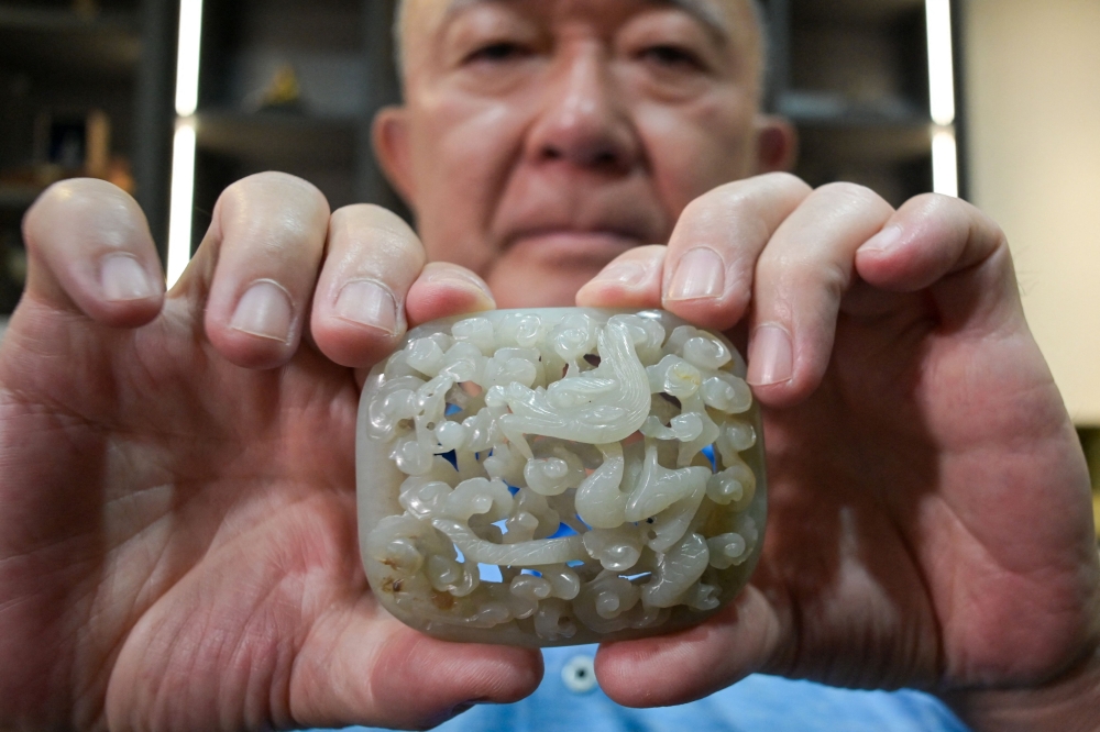 This picture taken on July 19, 2023 shows Chang Juben, chairman of Taiwan’s Association of Jade Collectors, displaying a Yuan dynasty (1217-1368) jade belt ornament showing a carving of a dragon among clouds, in Taipei. — AFP pic 