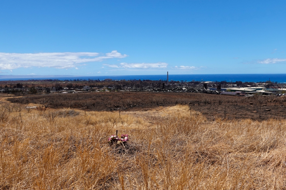 A lei of flowers sits on the grass above the fire ravaged town of Lahaina on the island of Maui in Hawaii, U.S., August 15, 2023. 