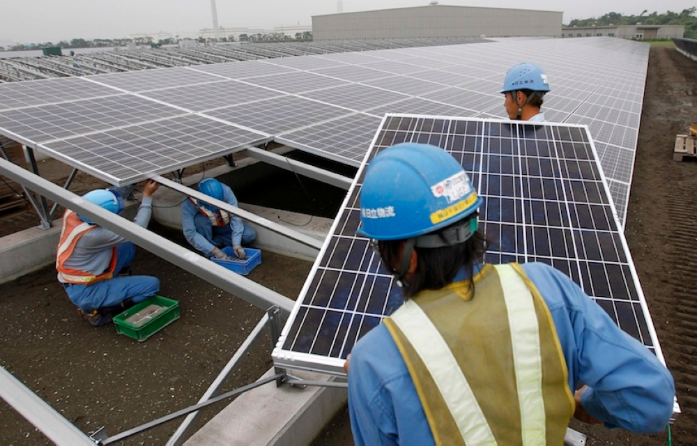 Workers set up a solar panel at a solar power field in this June 27, 2011 file photo. The growing use of solar photovoltaic cells, battery and electric two-wheeler industries in South-east Asia could potentially yield between US$90 billion and US$100 billion (RM417 billion to RM464 billion) by 2030. — Reuters pic