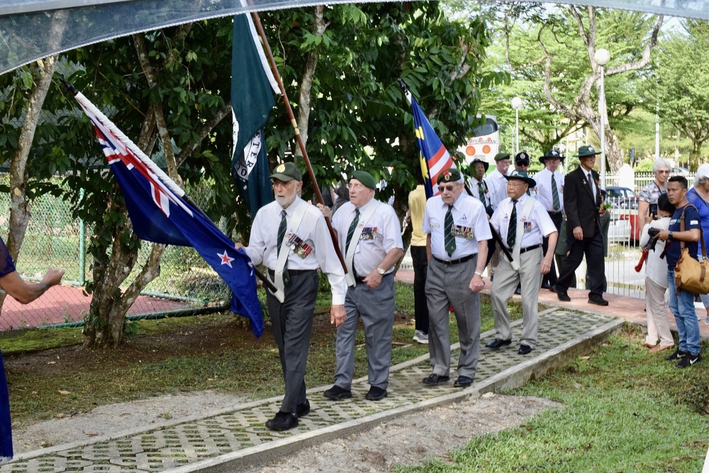 Veterans marching into the ceremony carrying the New Zealand, Malaya & Borneo Veterans Association and Malaysian flags. — Borneo Post pic 