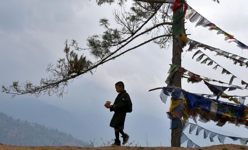 A boy in a traditional costume walks past prayer flags in Thimphu, Bhutan, April 16, 2016. — Reuters pic