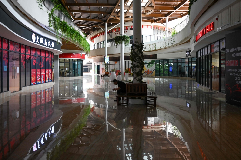 A man sits in the hallway in front of empty Forest City Outlet Mall, a development project launched under China's Belt and Road Initiative in Gelang Patah in Malaysia's Johor state on September 1, 2023. — AFP pic