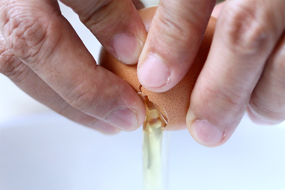 Crack each egg carefully to avoid broken pieces of eggshell.