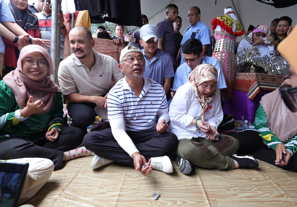 Yang di-Pertuan Agong Al-Sultan Abdullah Ri’ayatuddin Al-Mustafa Billah Shah and Raja Permaisuri Agong Tunku Azizah Aminah Maimunah Iskandariah play batu seremban during the Kembara Kenali Borneo ‘Pesta Keramaian Bersama Rakyat’ event at Bungai Beach, Bekenu September 9, 2023. — Bernama pic