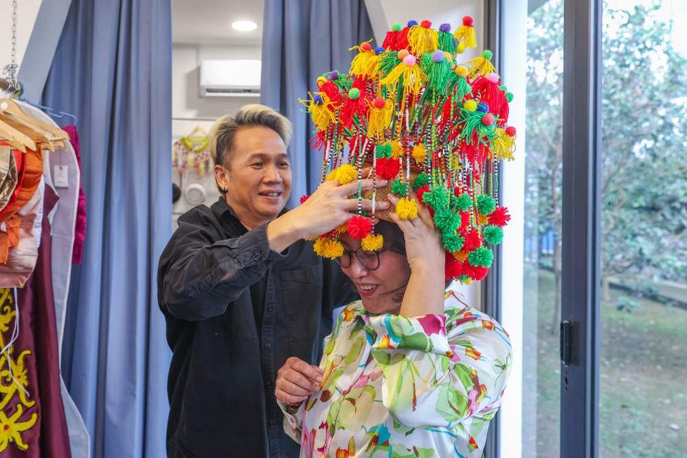 Fashion designer Gilbert Francis Untam helps Bernama reporter Lucia Terey John wear Dujung Manik, a type of traditional jewellery of the Iban people of Batang Rajang in Sarawak at Gilbert Headhunter's clothing boutique @G&Co in Seri Kembangan September 9, 2023. — Bernama pic