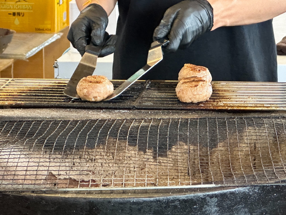 The patties are cooked over a charcoal grill and they test the temperature to ensure it's cooked.