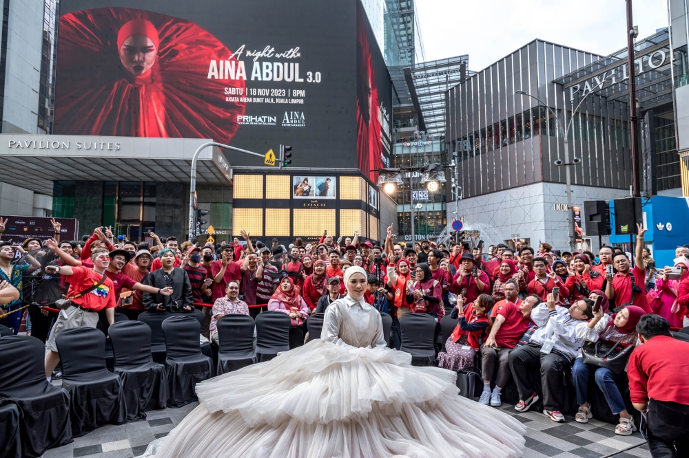 Aina Abdul with fans, known as Ainations, in front of her upcoming concert A Night with Aina Abdul 3.0 billboard in Bukit Bintang. — Picture by Firdaus Latif.