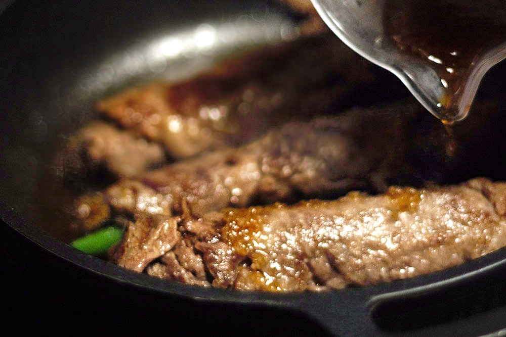 Pour the teriyaki sauce over the nearly fully cooked beef rolls as a finishing glaze.