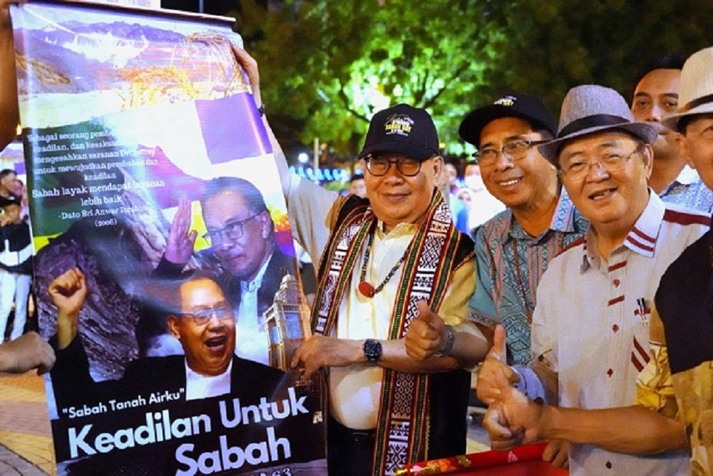 Datuk Seri Panglima Jeffrey Kitingan (centre) holds a banner at the ‘Kembara Apresiasi Sabah Day’ event. — Borneo Post pic