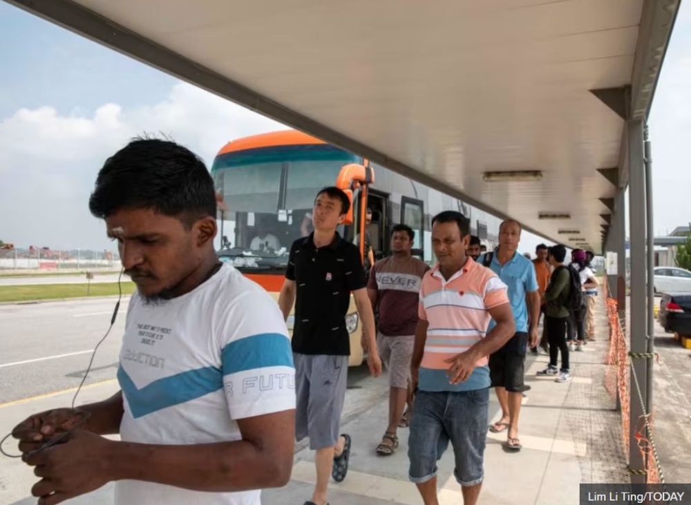 Migrant workers waiting to board a shuttle bus at Changi East Pass Office, near Tanah Merah Ferry Terminal, on Oct 1, 2023. — TODAY pic