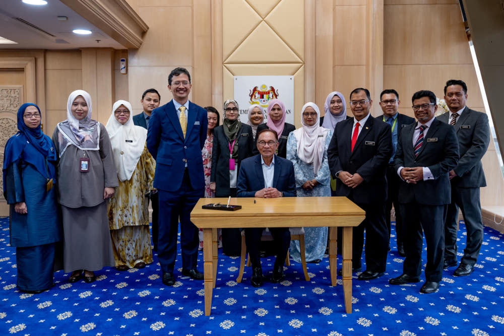 Prime Minister Datuk Seri Anwar Ibrahim poses for a picture with ministry staff during the signing ceremony for the official document of Budget 2024 at the Ministry of Finance, Putrajaya, October 3, 2023. — Picture from Facebook/Anwar Ibrahim 