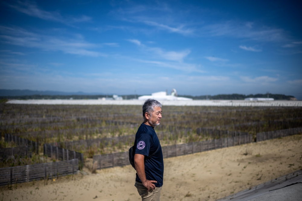 Japanese sake master Daisuke Suzuki looking at the area of his former sake brewery near Ukedo fishing port in Namie. — AFP pic